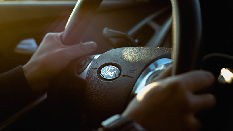 Jovem aprendiz ford - homem segurando um volante da ford - Foto por Jeremy Chen